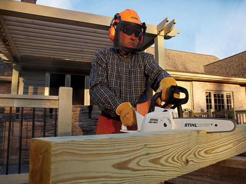 A man in protective gear uses a 2019 Stihl® 160 C-BQ Saw to cut through a large piece of lumber.